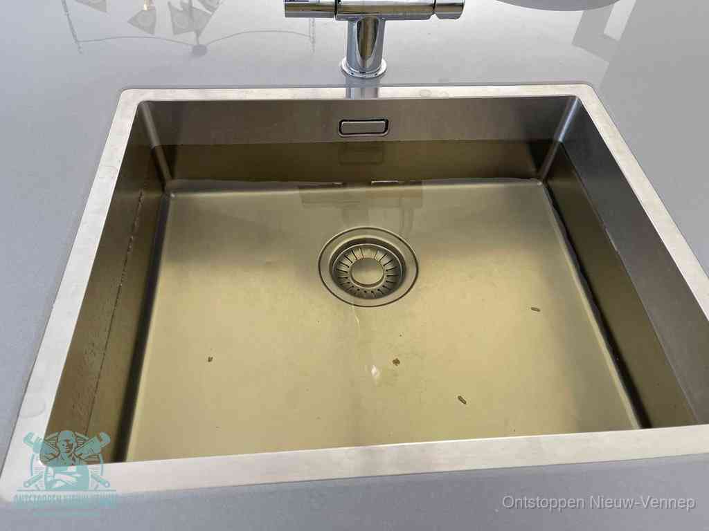 Stilstaand water in een rvs spoelbak dat niet wegloopt, een duidelijk signaal van een gootsteenverstopping in Nieuw-Vennep