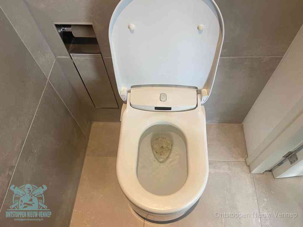 Een wit hangtoilet waarin een prop wc-papier op het water blijft drijven, een duidelijk signaal van een verstopte wc in Nieuw-Vennep