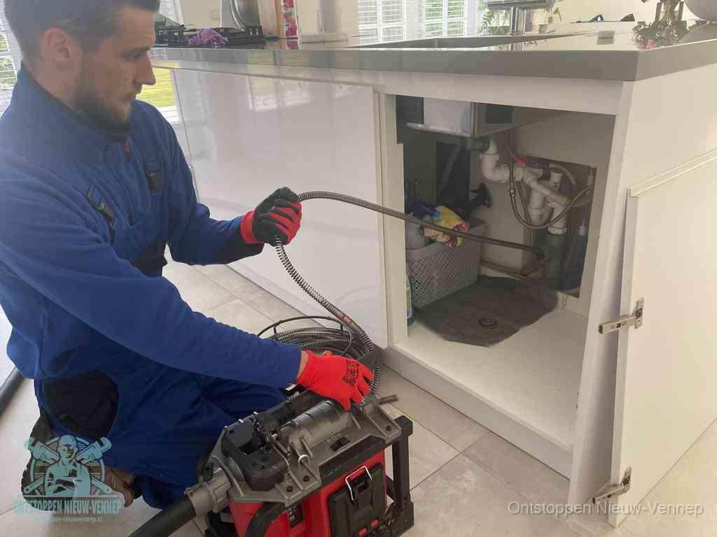 Een monteur reinigt de keukenafvoer grondig met een veermachine om terugkerende gootsteenverstoppingen te voorkomen in Nieuw-Vennep