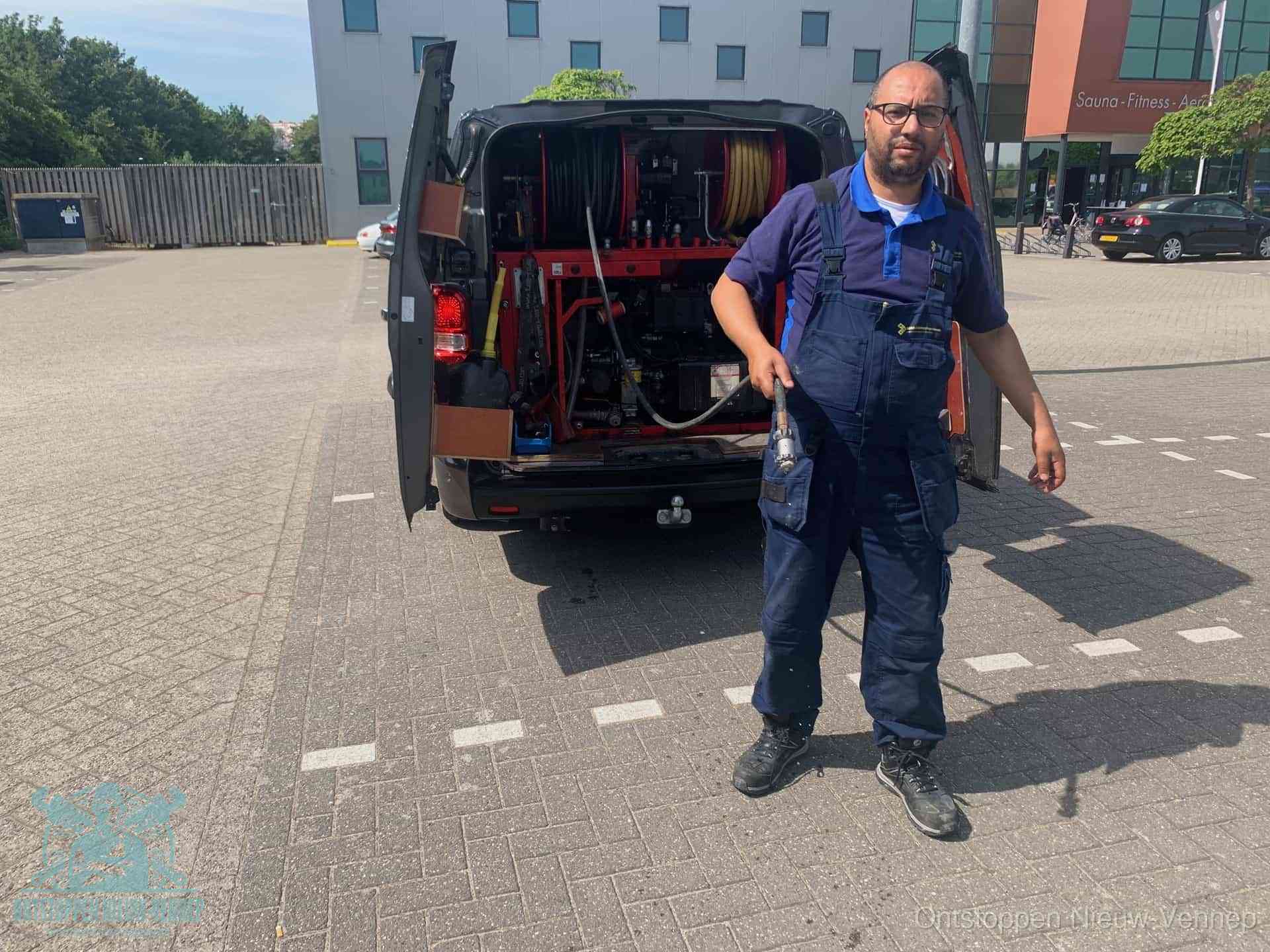 Een monteur bij zijn bestelbus met een hogedruk- en rioolreinigingsunit, klaar om de oorzaak van terugkerende wc-verstoppingen aan te pakken in Nieuw-Vennep