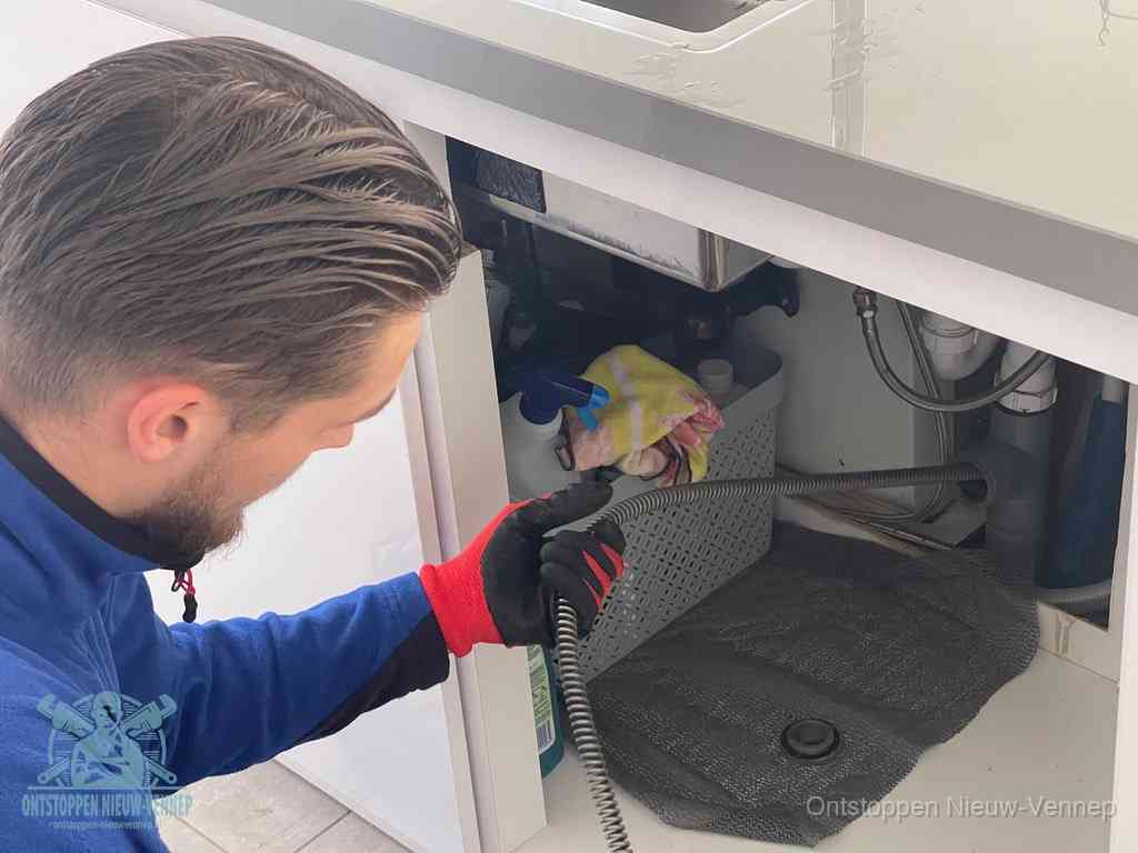 Een monteur voert een flexibele ontstoppingsveer in de afvoer om een verstopping voorbij de bocht van het toilet te bereiken in Nieuw-Vennep