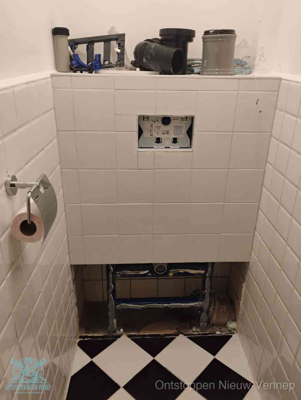 Een toiletruimte waar het hangtoilet en de inbouwreservoir-onderdelen zijn vrijgelegd voor onderhoud, periodiek nazicht voorkomt een wc-verstopping in Nieuw-Vennep