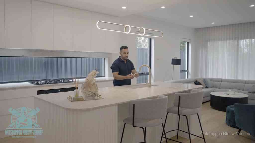 Een bewoner bij de keukenspoelbak die zelf aan de slag gaat met een verstopte gootsteen in Nieuw-Vennep